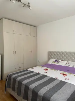 a bedroom with a large bed and white cabinets at IKONIJA guest house in Pečenjevce