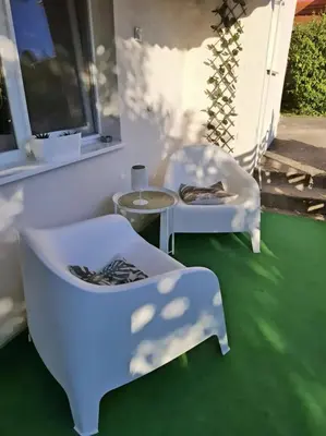 two white chairs and a table on a green floor at Apartmani Vlasina Sokobanja in Soko Banja