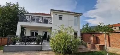 a white house with a balcony and a brick wall at Vila Elena in Niš