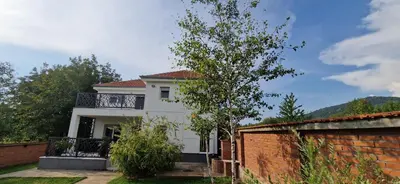 a white house with a balcony and a brick wall at Vila Elena in Niš