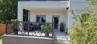 a white house with a gate and potted plants at Vila Elena in Niš