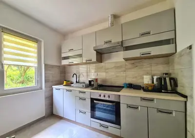a kitchen with white cabinets and a window at Apartman Berlin Sokobanja in Soko Banja