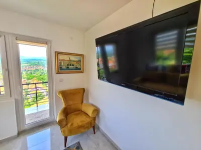 a living room with a large television and a chair at Apartman Berlin Sokobanja in Soko Banja