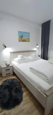a bedroom with a white bed with a black rug at Planinska idila in Kopaonik