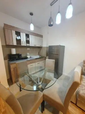 a kitchen with a glass table and a stainless steel refrigerator at HUGO APARTMAN Green Hill Kompleks- u blizini Akva Parka in Soko Banja