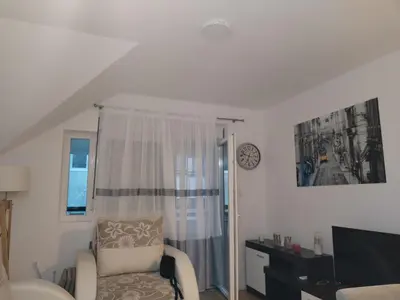 a living room with a chair and a television at HUGO APARTMAN Green Hill Kompleks- u blizini Akva Parka in Soko Banja