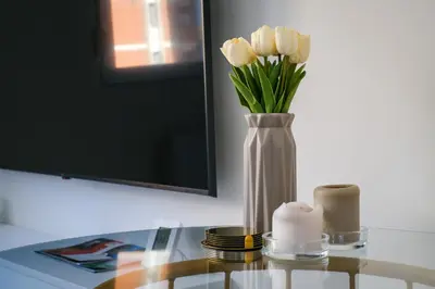 a vase of white roses on a table with a candle at Apartment in Niš, Center! brand-new in Niš