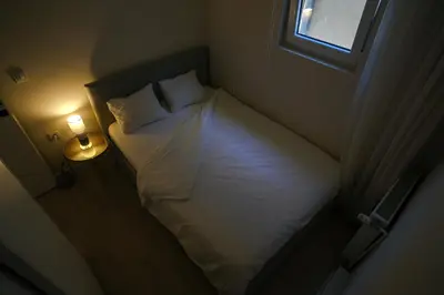 a small bedroom with a white bed with a window at Apartment in Niš, Center! brand-new in Niš