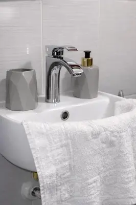 a bathroom sink with a white towel and a faucet at Nilton Apartmans in Niš