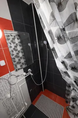 a bathroom with a shower with black and white tiles at Nilton Apartmans in Niš