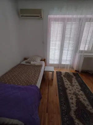 a bedroom with two beds and two windows and a rug at Villa Ema rooms in Niš