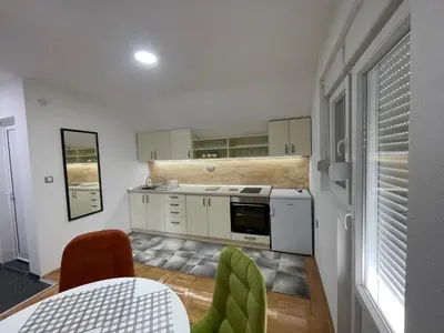 a kitchen with white cabinets and a table and chairs at Apartman La Vista Sokobanja in Soko Banja