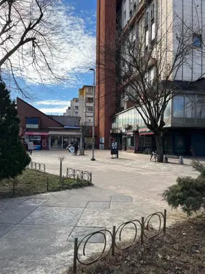 a street in a city with buildings and a bench at Apartman Centar in Pirot