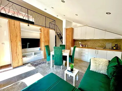 a living room with a green couch and a kitchen at Apartman Viny in Soko Banja