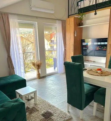 a living room with a table and green chairs at Apartman Viny in Soko Banja