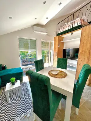 a dining room with a table and green chairs at Apartman Viny in Soko Banja