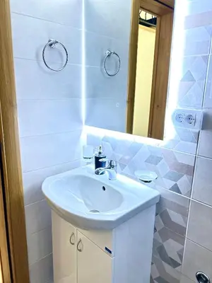 a white bathroom with a sink and a mirror at Apartman Viny in Soko Banja