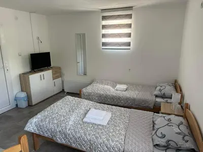a room with two beds and a television in it at Rooms Enna in Dimitrovgrad