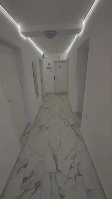 a hallway with a marble floor and white walls at Rooms Enna in Dimitrovgrad