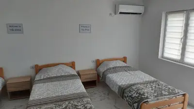 a room with three beds and a window at Rooms Enna in Dimitrovgrad