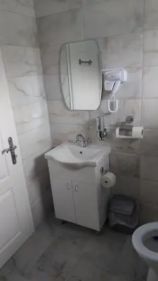 a bathroom with a sink and a mirror and a toilet at Rooms Enna in Dimitrovgrad