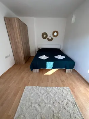 a small bedroom with a blue bed and a wooden floor at Boho Apartment in Niš