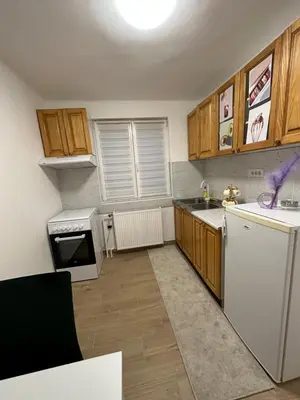 a kitchen with a white refrigerator and wooden cabinets at Boho Apartment in Niš