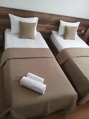 two beds in a hotel room with towels on them at Prenoćište SRBIJA in Surdulica