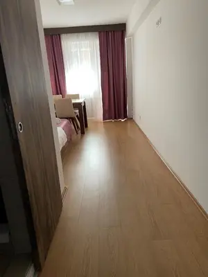 a room with a hallway with a wooden floor and a window at Prenoćište SRBIJA in Surdulica