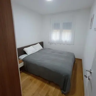 a bed in a white room with a window at APARTMANI PORTA INFINITAS centar in Vrnjačka Banja