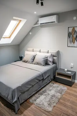 a bedroom with a large bed with a white wall at NOMAD Apartments in Niš