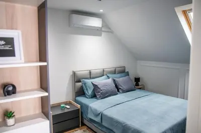 a small bedroom with a bed with blue pillows at NOMAD Apartments in Niš