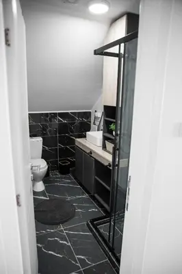 a black bathroom with a toilet and a sink at NOMAD Apartments in Niš