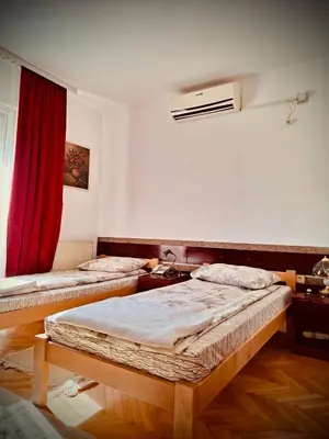 two beds in a room with a red curtain at Vila Grinka M in Zaječar