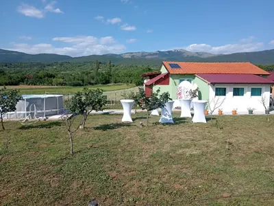 a field with two white chairs in front of a house at Apartman Sunce in Pirot