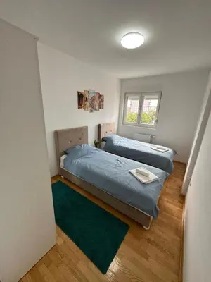 a bedroom with two beds and a green rug at Nis Apartment in Niš
