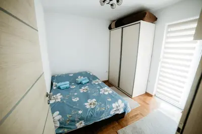 a small bedroom with a bed with a blue blanket at Apartman Ksenija in Vrnjačka Banja