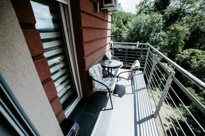 a balcony with a table and chairs on a house at Apartman Ksenija in Vrnjačka Banja