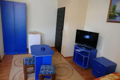 a living room with a tv and a blue table and stool at UTR Jagnjilo 1986 in Raška