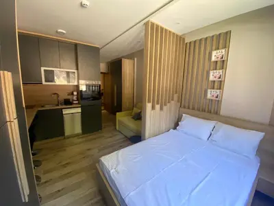 a bedroom with a white bed and a kitchen at Lana Lux Milmari Resort in Kopaonik