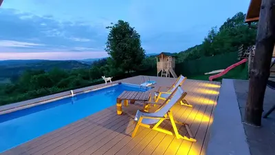 a deck with two chairs and a table next to a pool at Vikendica Ristic in Knjazevac.