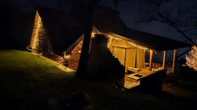 a cabin lit up at night with christmas lights at Vikendica Ristic in Knjazevac.
