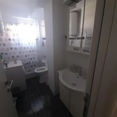 a white bathroom with a sink and a toilet at Apartman Mika **Centar ** in Kruševac