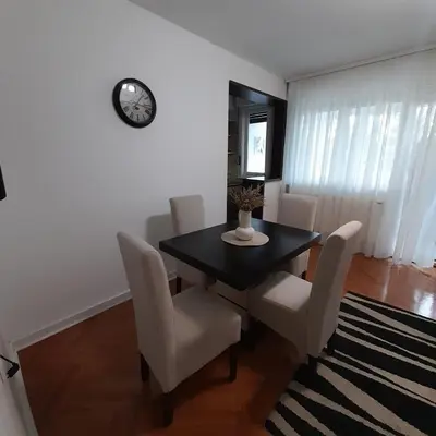 a dining room with a table and chairs and a clock at Apartman Mika **Centar ** in Kruševac