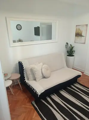 a white couch in a living room with a mirror at Apartman Mika **Centar ** in Kruševac