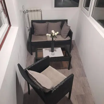 a room with a chair and a table with a vase of flowers at Apartman Mika **Centar ** in Kruševac