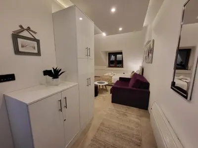 a living room with white cabinets and a couch at Kloudscape Apartman Milmari Resort & Spa in Kopaonik