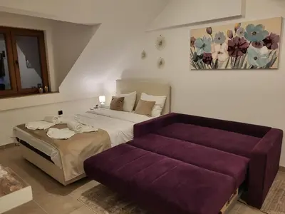 a bedroom with a bed and a purple couch at Kloudscape Apartman Milmari Resort & Spa in Kopaonik