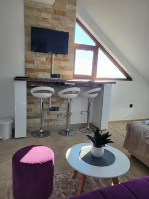 a living room with three bar stools and a tv at Kloudscape Apartman Milmari Resort & Spa in Kopaonik