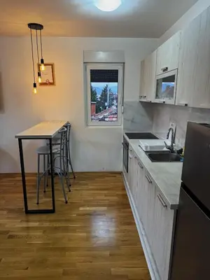 a kitchen with a counter and a table with stools at Niš East gate APT with balcony and free private Parking in Donja Vrežina
